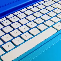 Niebieski laptop z białymi klawiszami. Dowiedz się, jak podłączyć klawiaturę do laptopa, aby ułatwić sobie pisanie.