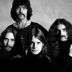 Czterech członków zespołu Black Sabbath, twórców kultowych utworów, pozuje do czarno-białego zdjęcia.
