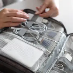 W organizerze na bagaż podręczny znajduje się biały powerbank, kable i ładowarki.