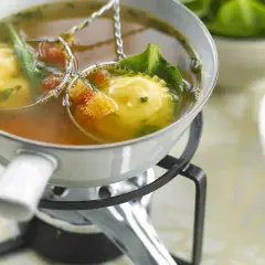 Raviolis dans un bouillon, accompagnés de légumes verts et de tomates. Une délicieuse fondue viande blanche à déguster.