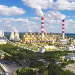 Ogromna elektrownia Bełchatów z kominami i chłodniami, emitująca białe kłęby pary. Zastanawiasz się, ile węgla spala elektrownia Bełchatów?