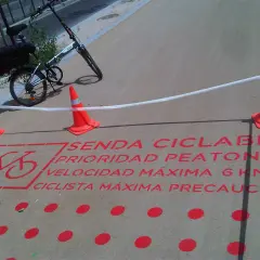 Bicicleta plegable en sendas ciclables con señalización de prioridad peatonal y límite de velocidad.