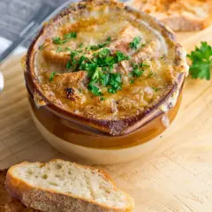 Soupe à l'oignon gratinée, un classique réconfortant. Croutons dorés, fromage fondu et persil frais. Parfait pour une recette maison.