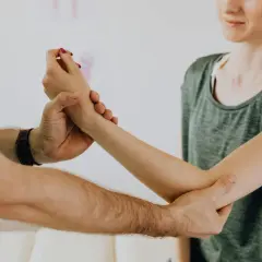Fizjoterapeuta bada rękę pacjentki, pomagając jej w leczeniu łokcia tenisisty.
