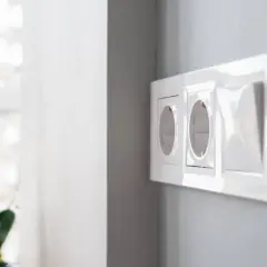 Instalación eléctrica moderna: cómo poner un enchufe donde no hay. Dos tomas de corriente y un interruptor en una pared gris.