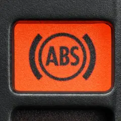 Pomarańczowy przycisk z symbolem ABS na desce rozdzielczej samochodu.