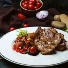 Soczysty udziec wołowy z salsą pomidorową i ziemniakami.