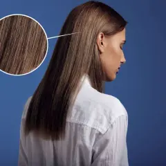 Primer plano de un cabello castaño sedoso, con un círculo que amplía los detalles. Parece que el pelo está en pausa, esperando un nuevo estilo.