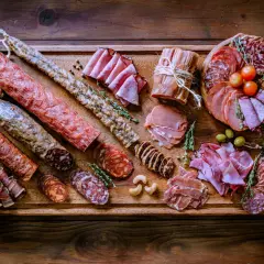 Bei taglieri di salumi e formaggi, un'abbondante selezione di prelibatezze italiane su un tagliere di legno rustico.