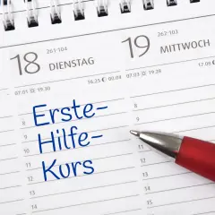 Ein roter Stift markiert "Erste-Hilfe-Kurs" in einem Kalender. Die Frage "wie lange gilt ein erste hilfe kurs" wird hier visuell thematisiert.