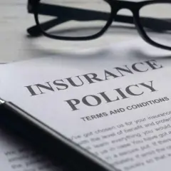 Okulary, lupa i dokument "Insurance Policy" symbolizują analizę polisy PZU po śmierci teścia.