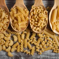 Vier Holzlöffel mit verschiedenen Nudelsorten: Maccheroni, Fusilli, Cavatappi und Penne. Eine Frage, wie viel Gramm Fusilli pro Person?