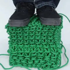 Pieds chaussés sur un cube de tricotage 3D vert vif, démontrant la solidité de la maille.