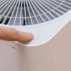 Dedo presionando el botón de encendido de un purificador de aire con filtro de ozono.