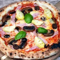 Pizza Capriciosa z klasycznymi składnikami: szynką, pieczarkami, karczochami i oliwkami.