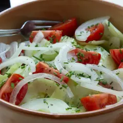 Frischer Tomaten-Gurken-Salat mit Zwiebeln, Schnittlauch und einem Hauch Balsamico-Dressing.