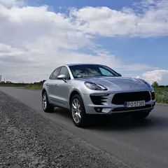 Srebrny Porsche Macan na drodze. To właśnie Porsche produkuje te luksusowe SUV-y.