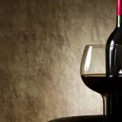 Ciemna butelka wina i kieliszek na tle. W jakiej temperaturze zamarza wino? Poniżej 0°C, ale zależy od zawartości alkoholu.