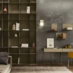Ein moderner schreibtisch im wohnzimmer, neben einem Sofa und einem großen Regal. Ein gelber Stuhl steht davor.