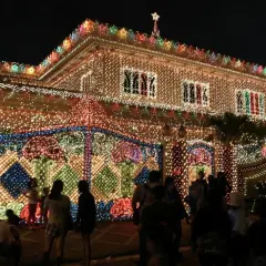 Ein Haus auf den Philippinen, das mit Tausenden von Lichtern für Weihnachten geschmückt ist. Die Fassade und der Zaun leuchten hell.