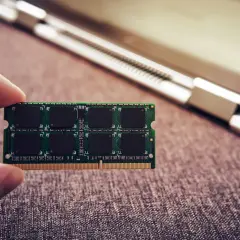 Palec trzyma moduł RAM do laptopa.