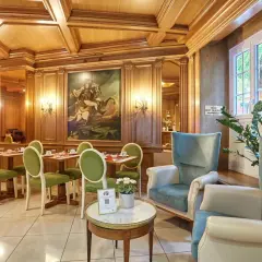 Elegancka jadalnia w hotelu Murat z zielonymi krzesłami i obrazem konnym.