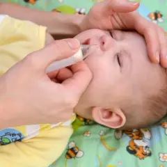 Mani delicate aiutano un neonato di 1 mese con il raffreddore, usando un aspiratore nasale per liberare il piccolo nasino.