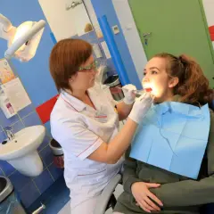 Dentystka bada zęby młodej pacjentki w gabinecie stomatologicznym.