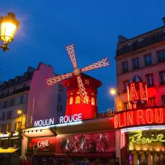 Le Moulin Rouge illuminé la nuit. La durée du spectacle est une question que beaucoup se posent avant de venir admirer ce lieu emblématique.