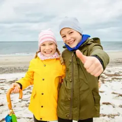 Zwei Kinder am Strand, bereit für Abenteuer, egal was kann man bei schlechtem Wetter machen.