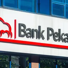 Logo Banku Pekao na białej fasadzie budynku, z niebieskimi oknami powyżej.