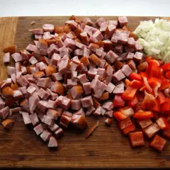 Pokrojona kiełbasa, papryka i cebula na desce do krojenia, gotowe do przygotowania pysznego leczo z kiełbasą.
