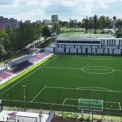 Nowy stadion Polonii Bytom z zieloną murawą, trybunami w kolorach czerwonym i niebieskim oraz nowoczesnym budynkiem klubowym.