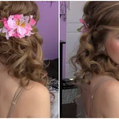 Acconciatura laterale capelli medi con boccoli morbidi e un fiore rosa.