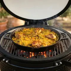 Paella de poulet et légumes cuite dans une poêle sur un kamado grill.