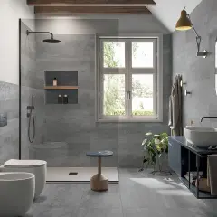 Bagno moderno con piastrelle grigie effetto pietra, doccia walk-in, WC, bidet e lavabo. Ideale per la sostituzione piastrelle bagno.