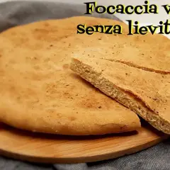 Focaccia veloce senza lievitazione su tagliere di legno. Una fetta è stata tagliata per mostrare la morbidezza.