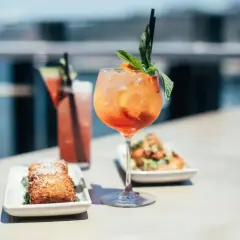 Aperol Spritz z miętą i pomarańczą, obok drink z plasterkiem arbuza i przekąski. Idealne na aperitivo, zastanawiasz się jakie prosecco do Aperola?