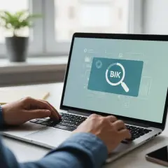 Osoba pisze na laptopie, na ekranie którego widnieje lupa i napis BIK.