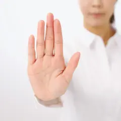 Dłoń uniesiona w geście stop. To symbol asertywności i stawiania granic.