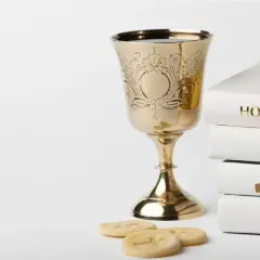 Złoty kielich, hostie, różaniec i stos białych ksiąg, w tym "Holy Bible". Symbolika sakramentu, jak akt chrztu.