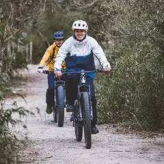 Dwóch rowerzystów pokonuje trasę przez las, ciesząc się aktywnością na świeżym powietrzu.