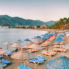 Plaża w Marmaris z rzędami leżaków i parasoli, idealne miejsce na relaks. W tle góry i hotele.