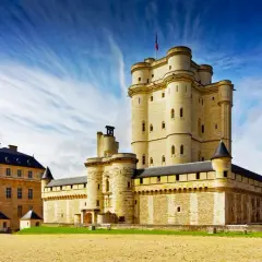 Le majestueux **Château de Vincennes** se dresse sous un ciel bleu éclatant, ses tours imposantes rappelant des siècles d'histoire.