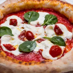 Deliciosa masa de pizza napolitana con tomate, mozzarella fresca, tomates cherry y hojas de albahaca.