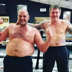 Tyson Fury's build is showcased as he poses shirtless with Ricky Hatton in a boxing ring, both flexing.