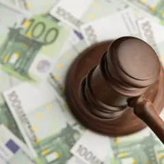 Młotek sędziowski na tle banknotów 100 euro.