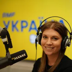 Uśmiechnięta prezenterka w słuchawkach przed mikrofonem. Na tle logo RMF MAXXX, które można usłyszeć na tej samej częstotliwości.