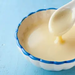 Cuchara con leche evaporada, un ingrediente cremoso y dulce, ideal para postres.