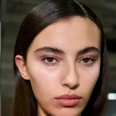 Primer plano de una joven con cejas pobladas y mirada intensa. Su piel luce natural y sus labios están ligeramente brillantes.